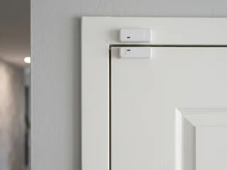 Magnetic door contact sensor installed on a door frame in a Singapore property; magnet on the door, reed switch on the fixed frame